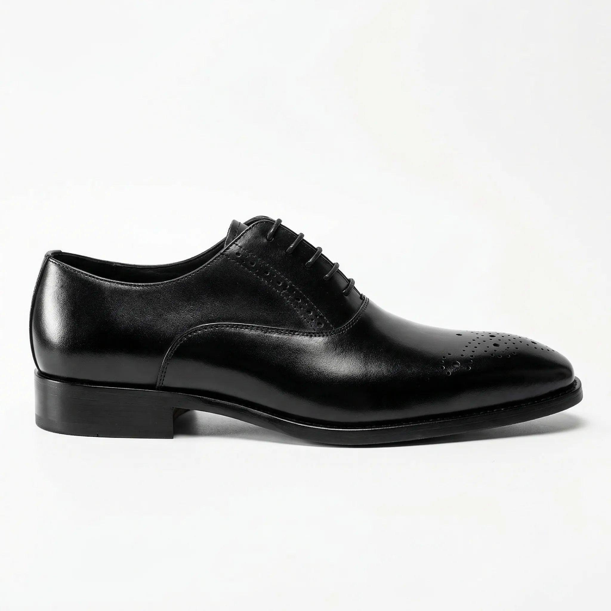 Black leather Oxford dress shoe with brogue detailing on toe, side view, white background.