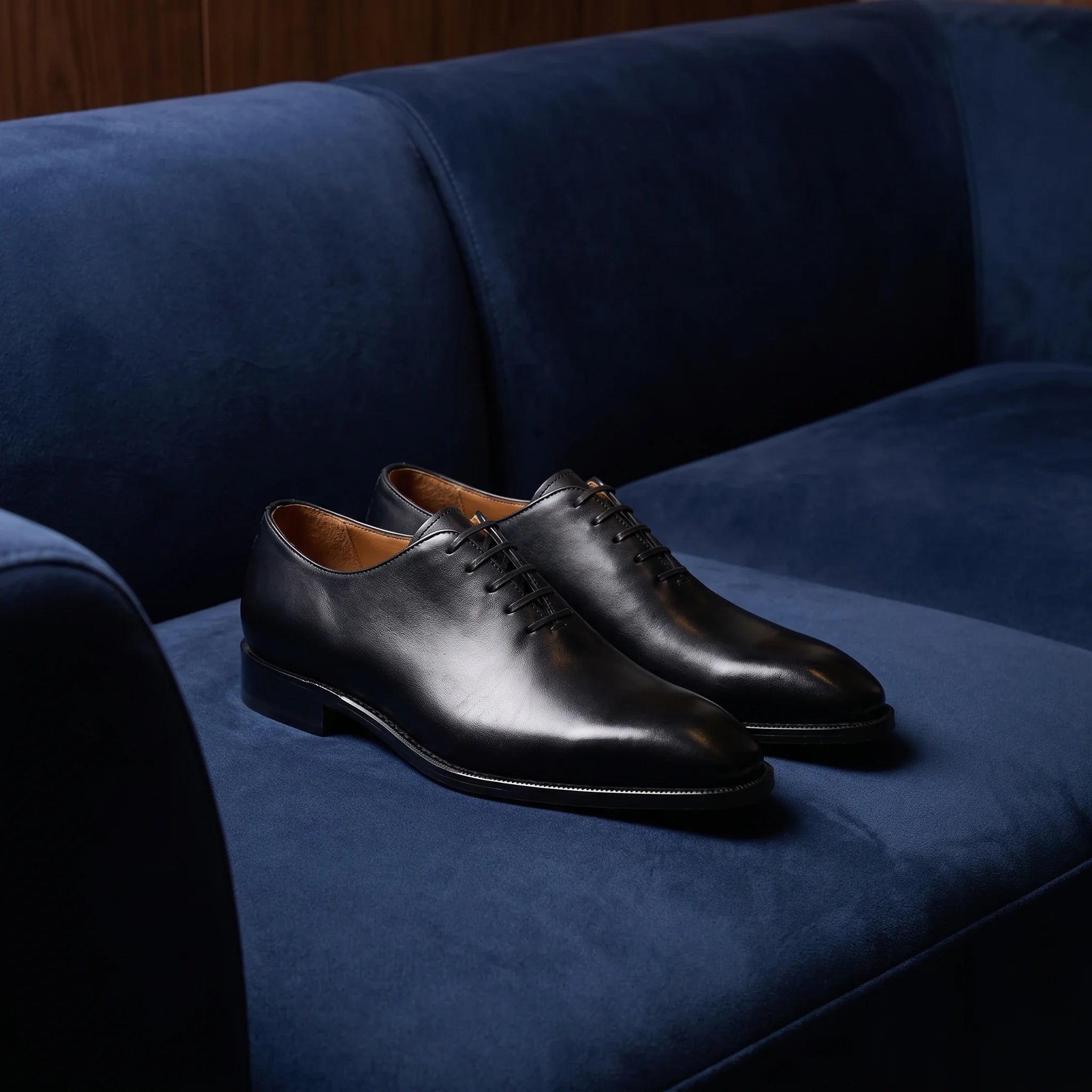 Handmade brogue oxford shoe in full grain leather placed on an elegant and minimalist blue suede sofa