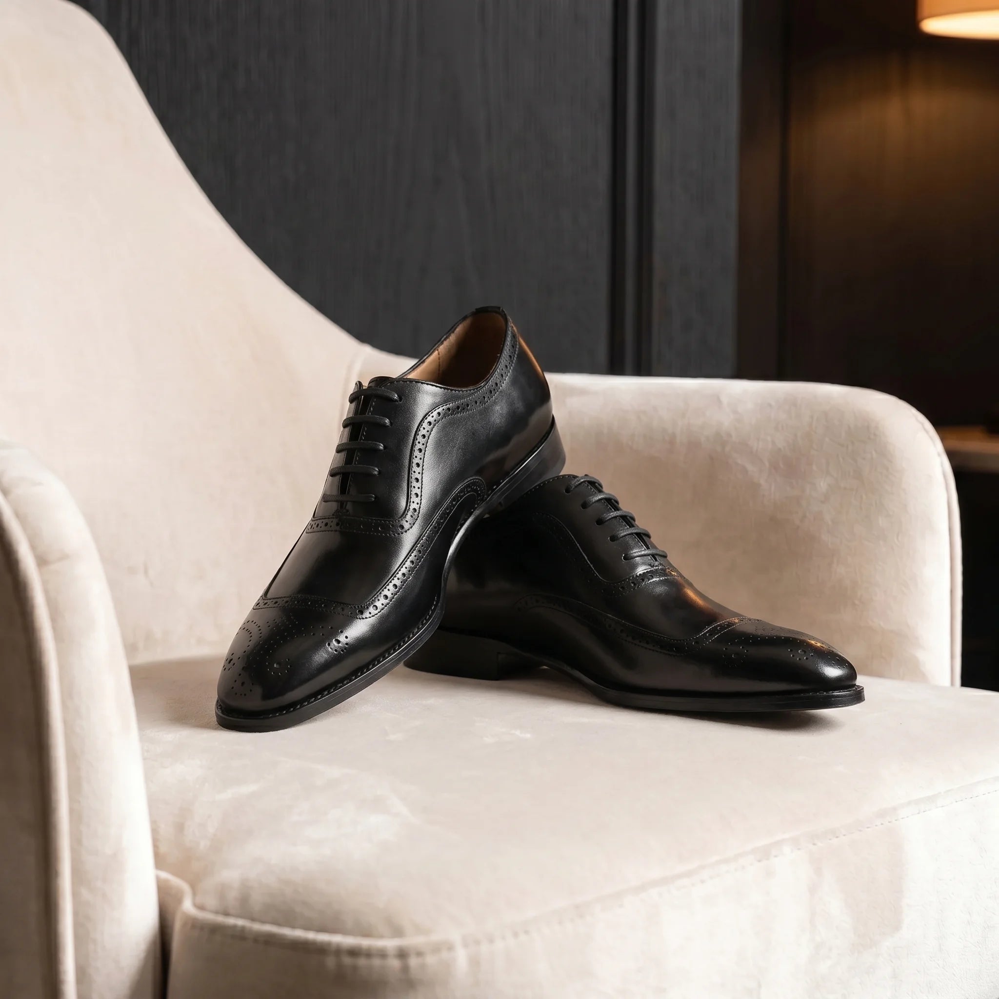 Handmade full-grain leather oxford brogue shoe placed on an elegant and minimalist velvet chair
