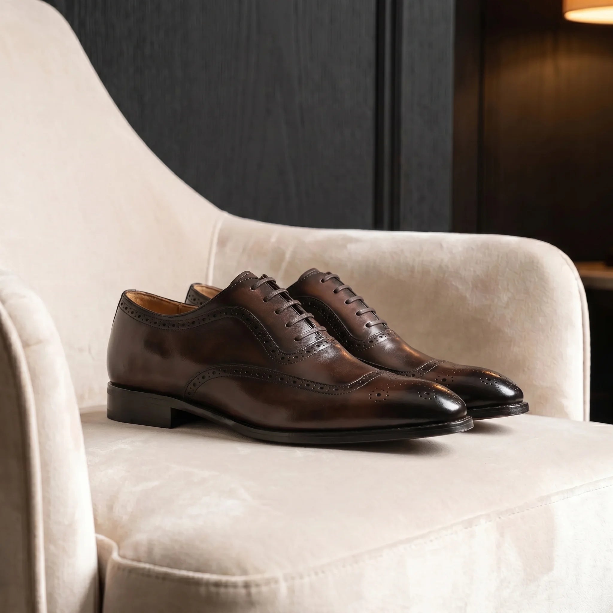 Handmade full-grain leather oxford brogue shoe placed on an elegant and minimalist velvet chair