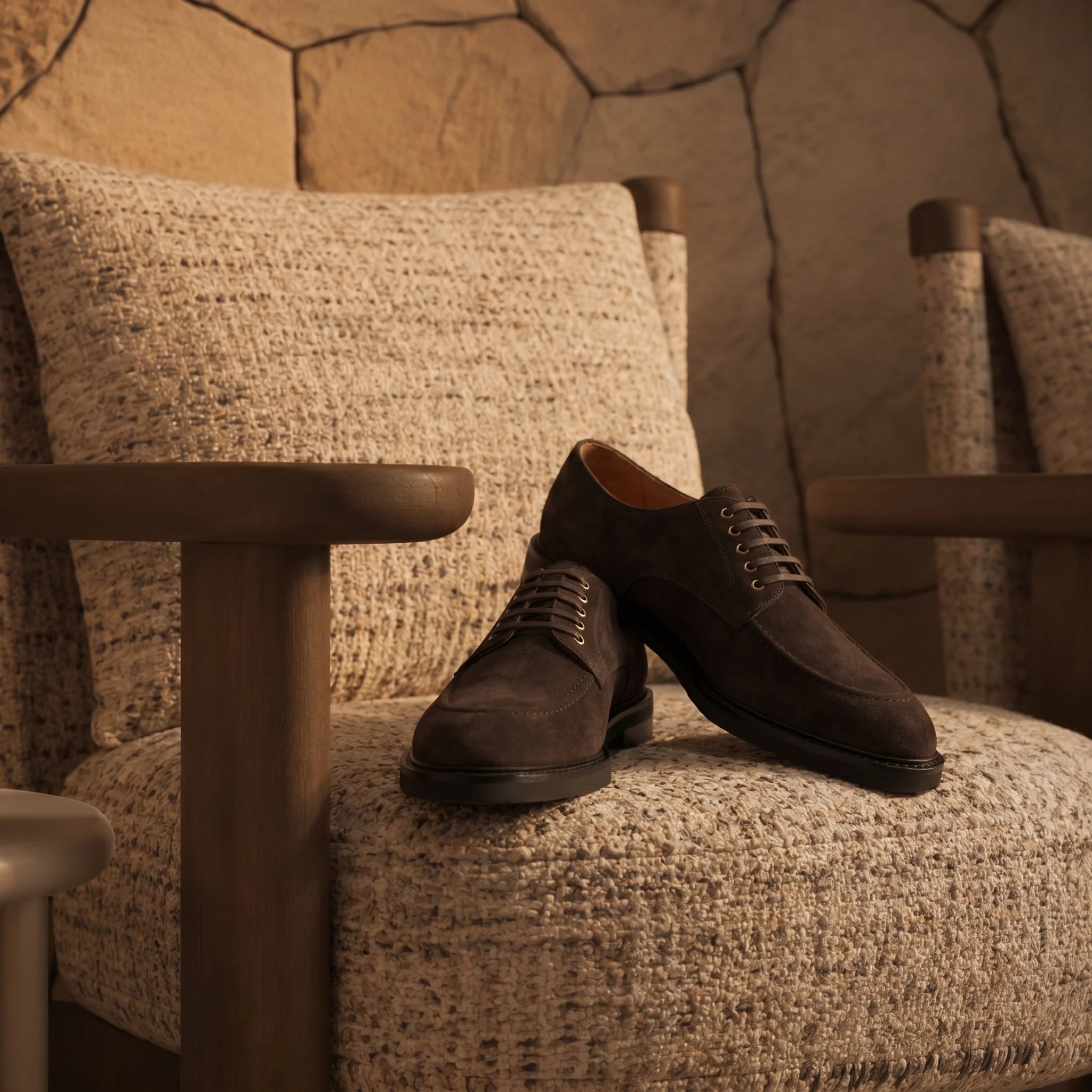 Handcrafted suede derby shoe placed on a chair in an elegant, luxurious room